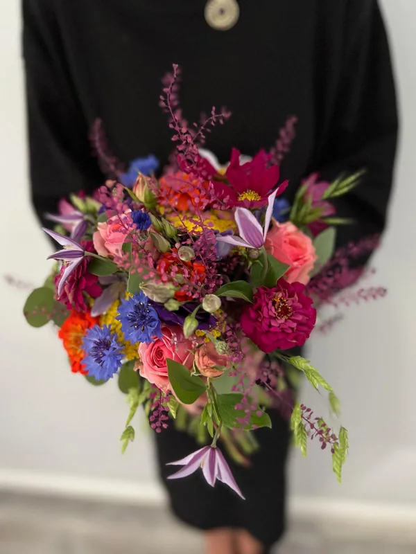Farbenfroher Brautstrauß mit roten, rosa, blauen, gelben und orangefarbenen Blüten