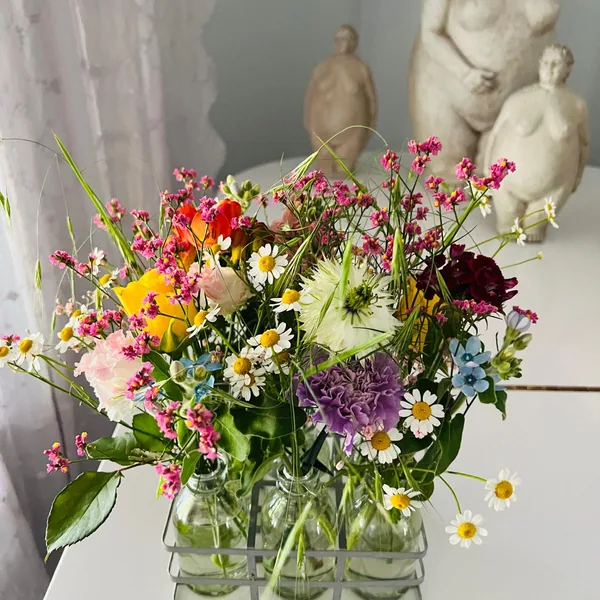 Lockeres Arrangement aus bunten Sommerblumen in mehreren kleinen Glasvasen