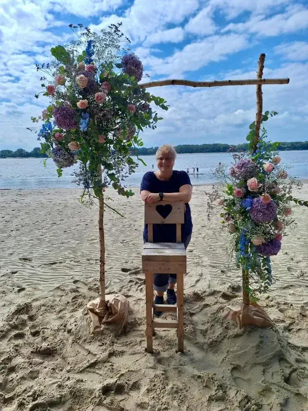 Rustikaler Traubogen am Strand mit großen Arrangements in Rosa, Flieder und Blau
