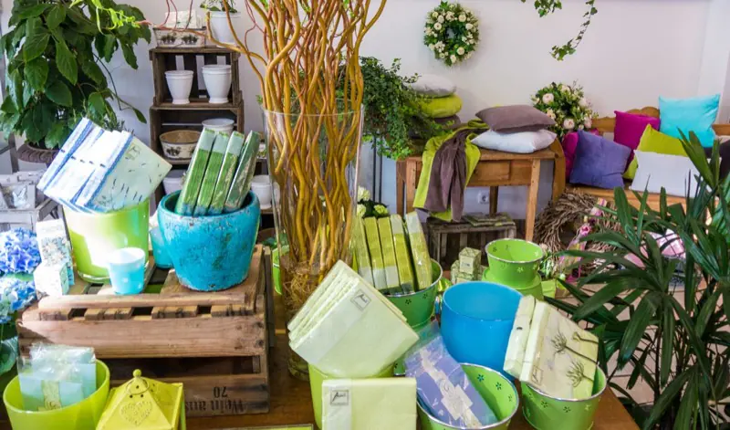 Dekotisch im Laden mit Übertöpfen, Geschenken und Windlichtern in Grün und Türkis