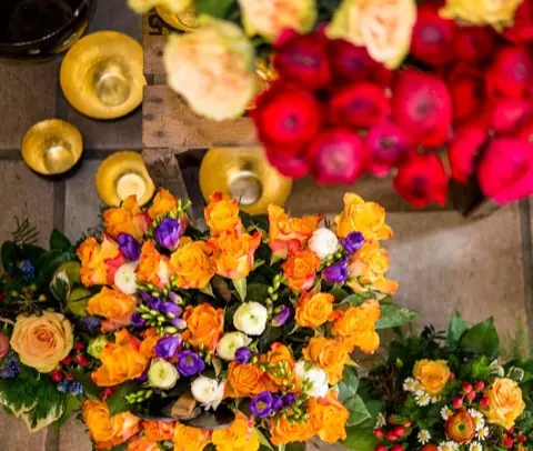 Mehrere bunte Sträuße mit orangen Rosen, Ranunkeln und Freesien von oben