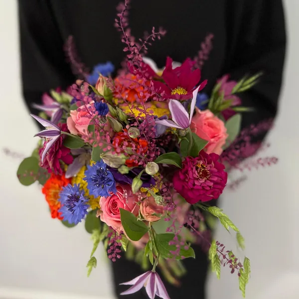 Handgebundener Strauß mit Rosen, Kornblumen und Clematis in kräftigen Sommerfarben