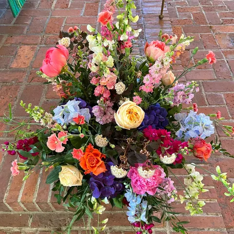 Locker gearbeitetes Arrangement mit Rosen, Hortensien und Sommerblumen in kräftigen Farben