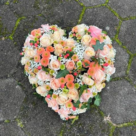 Herz aus cremefarbenen Rosen, apricotfarbenen Chrysanthemen und Efeu