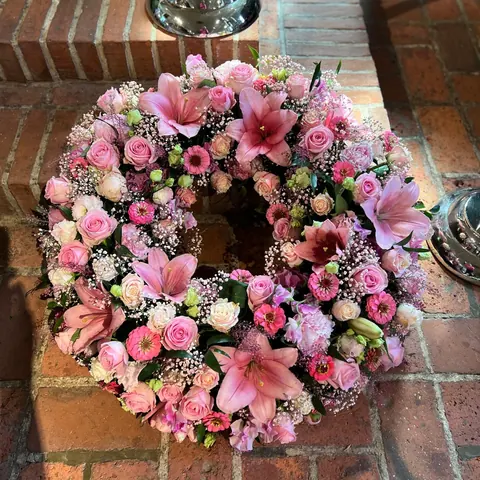 Trauerkranz aus rosa Lilien, Rosen, Zinnien und Schleierkraut