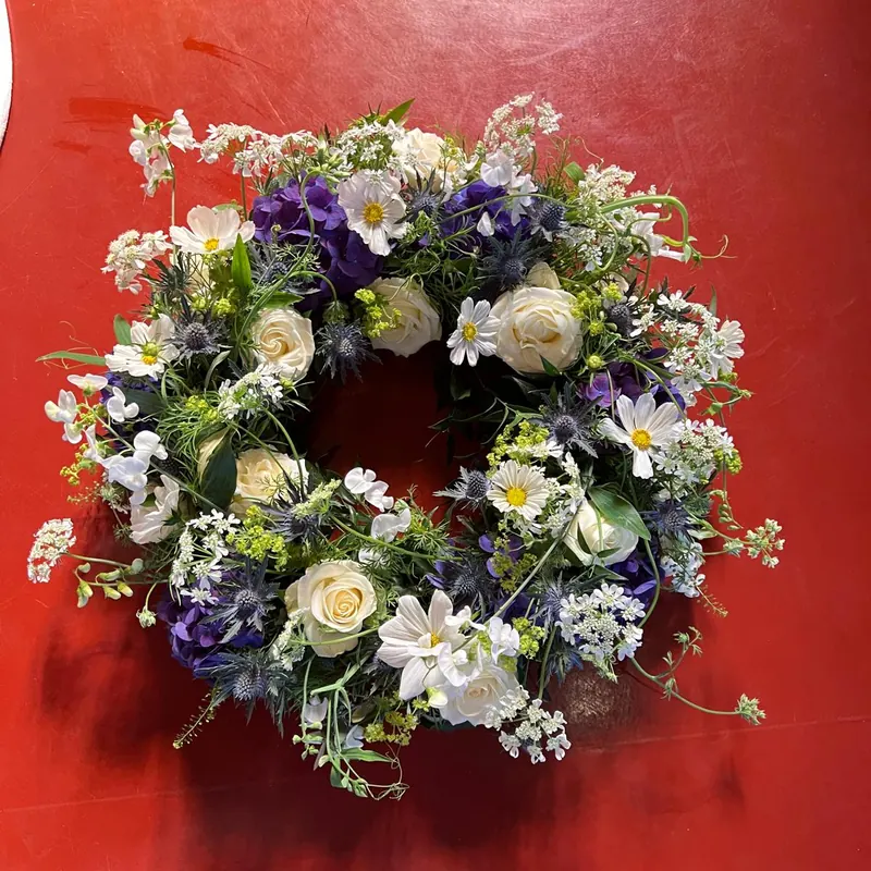Trauerkranz in Weiß und Violett mit Rosen, Kosmeen und Disteln